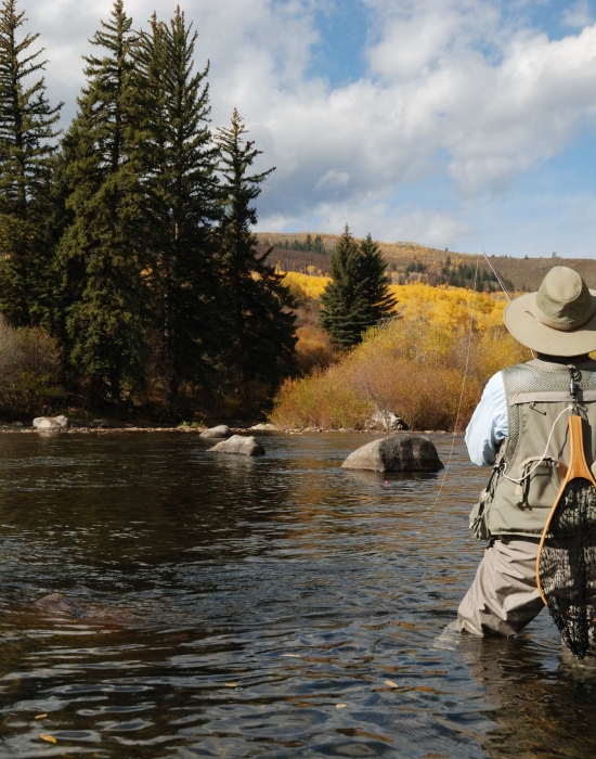 A person fly-fishing in a river at Vail CO