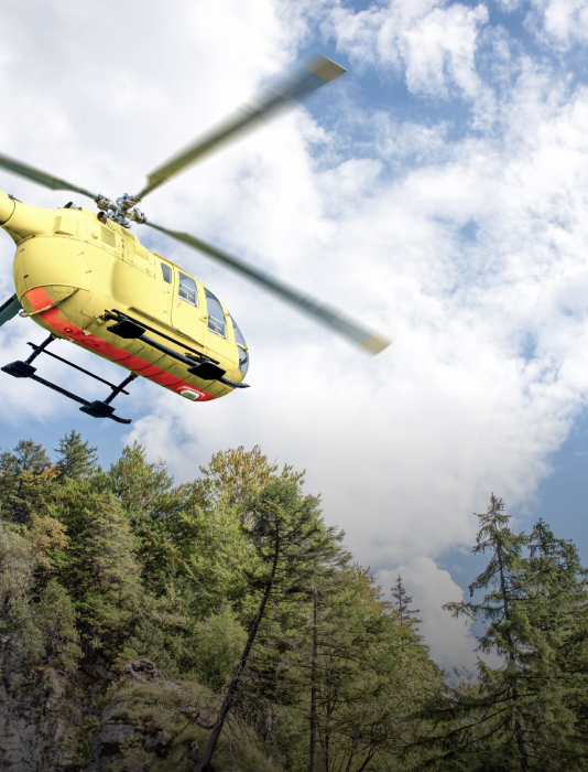 A helicopter flying over the mountain trees of Vail CO