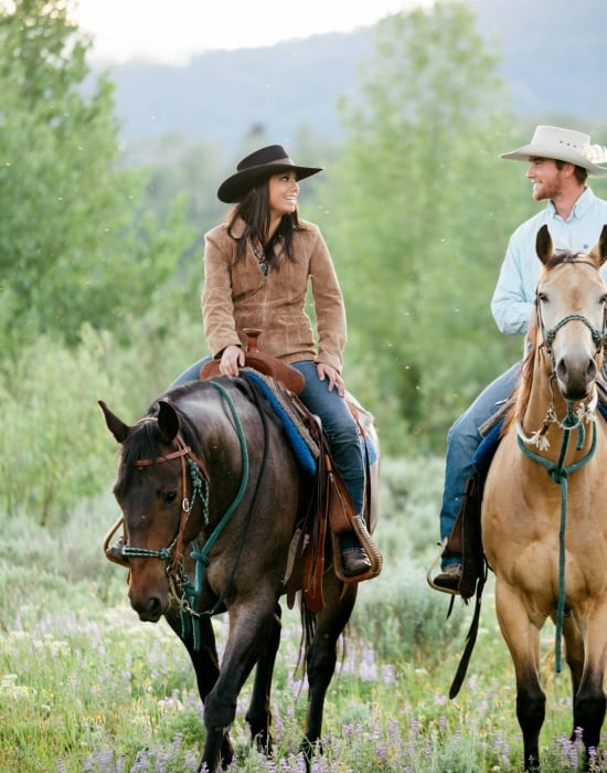A couple riding on horseback through a trail in Vail CO