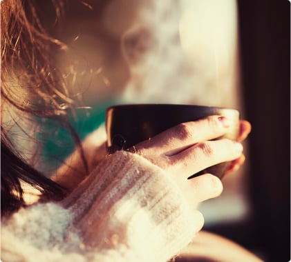 A person holding a hot cup of coffee
