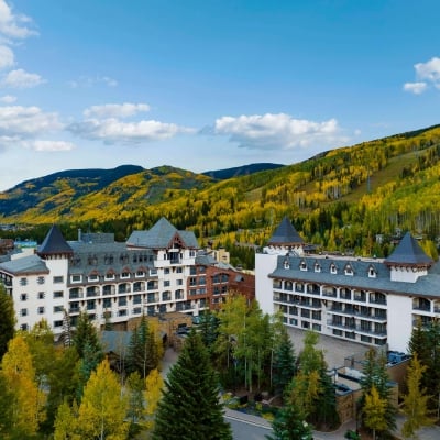 Stunning aerial view of The Hythe Vail resort nestled among vibrant yellow and green autumn trees on the mountainside.