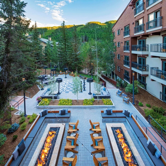 verhead view of a summer après deck at The Hythe featuring fire pits, cozy seating, and a large outdoor chess set.